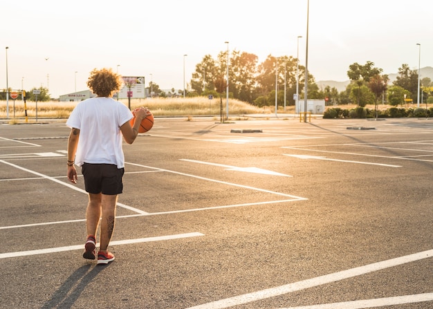 Hombre jugando baloncesto en la cancha durante el día soleado