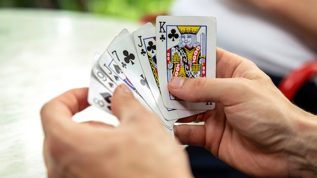 Un hombre jugando a las cartas con otras personas sosteniendo una baraja.
