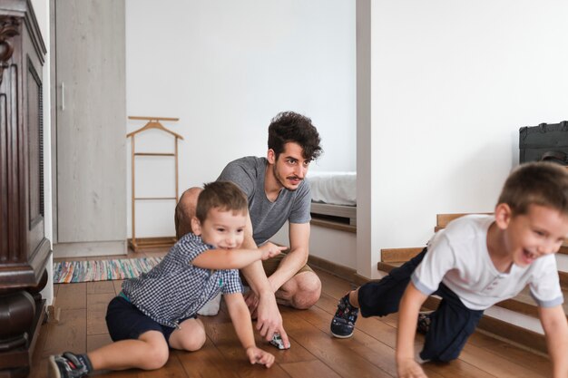 Hombre jugando a sus hijos en el piso de madera dura en casa