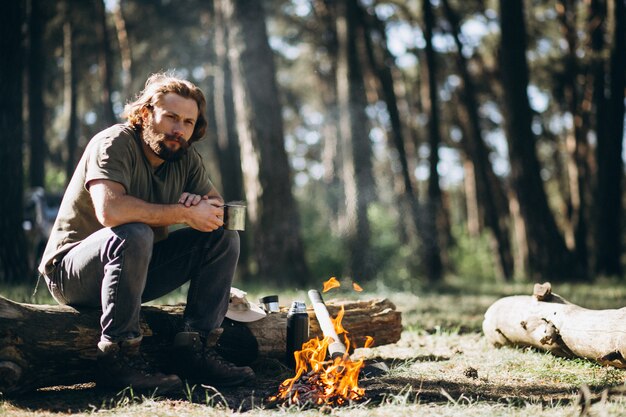 Hombre junto al fuego en el bosque