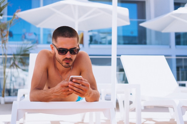 Hombre junto a la piscina con teléfono