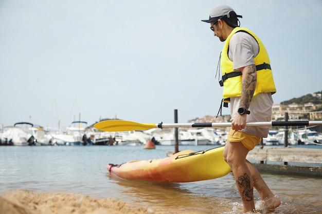 Hombre en kayak con gorra y chaqueta de seguridad amarilla