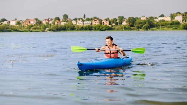 Hombre kayak en un kayak inflable sobre el lago