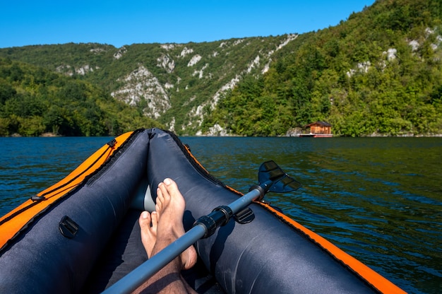 Foto gratuita hombre en kayak en el lago rodeado de colinas cubiertas de verdes