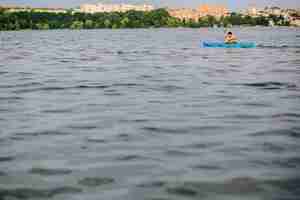 Foto gratuita un hombre en kayak en la superficie ondulada del agua del lago