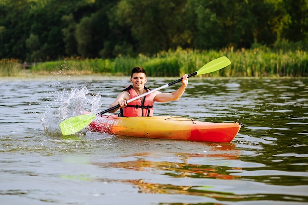 Hombre kayakista salpicaduras de agua mientras kayak en el lago