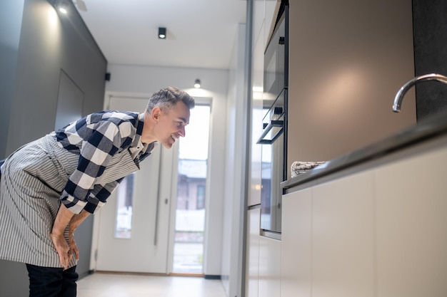 Foto gratuita hombre de lado a la cámara inclinada hacia el horno viendo