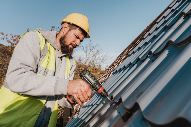 Foto gratuita hombre de lado trabajando en el techo con un taladro