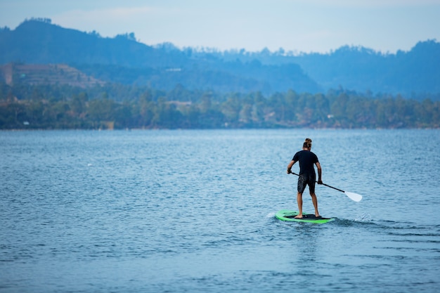 Un hombre en el lago monta una tabla de sup.