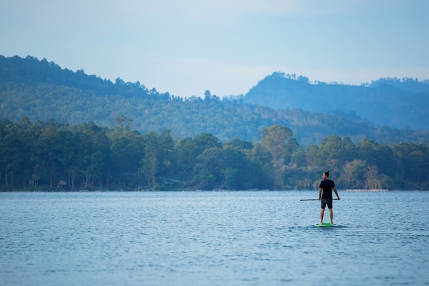 Un hombre en el lago monta una tabla de sup.