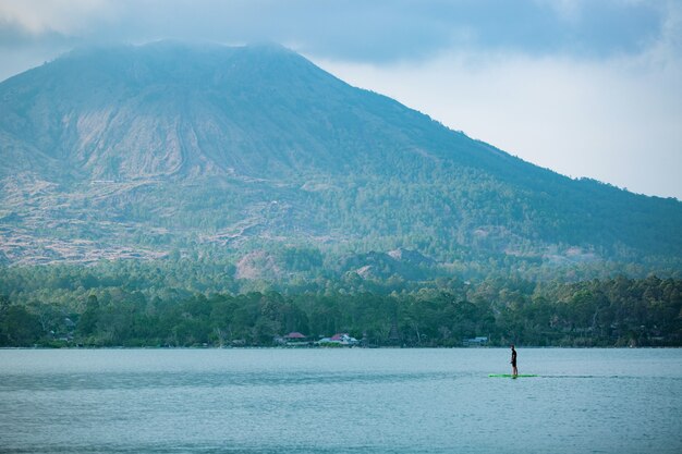 Un hombre en el lago monta una tabla de sup.