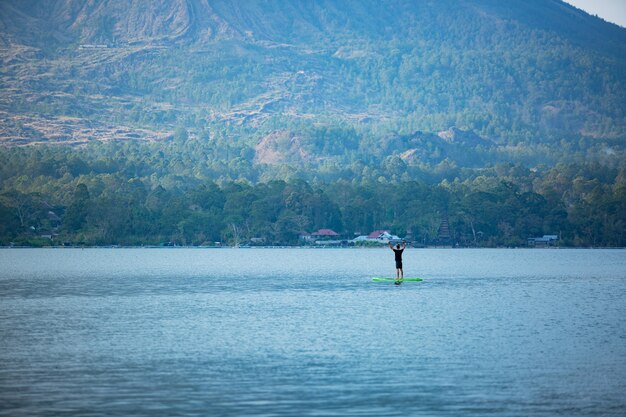 Un hombre en el lago monta una tabla de sup.