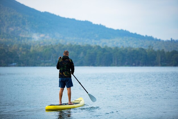 Un hombre en el lago monta una tabla de sup.