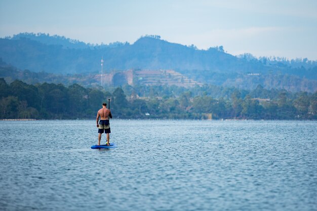 Un hombre en el lago monta una tabla de sup.