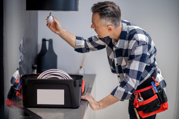 Foto gratuita hombre con lámpara en mano extendida cerca de campana de cocina