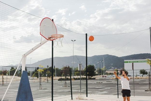 Hombre lanzando baloncesto en aro