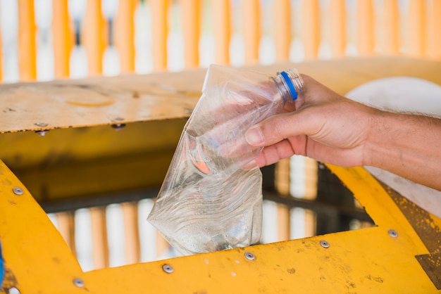 Hombre lanzando botella de plástico en papelera de reciclaje