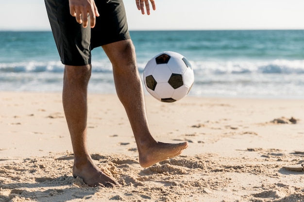 Hombre lanzando pelota arriba jugando juego en la playa