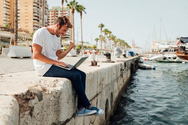 Hombre con laptop celebrando junto al río