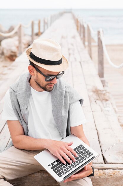 Hombre con laptop en muelle de playa