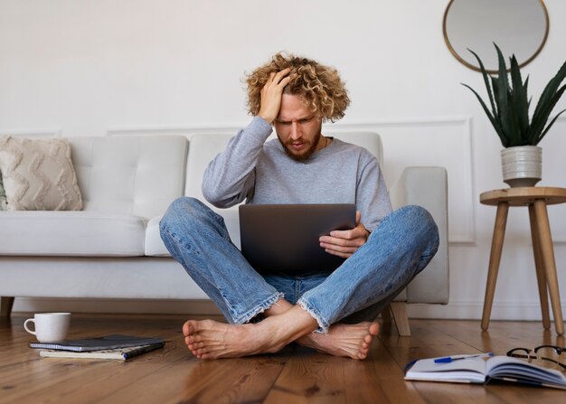 Hombre con laptop en piso tiro completo