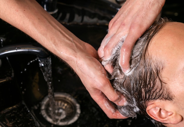 Hombre lavando el cabello de un cliente