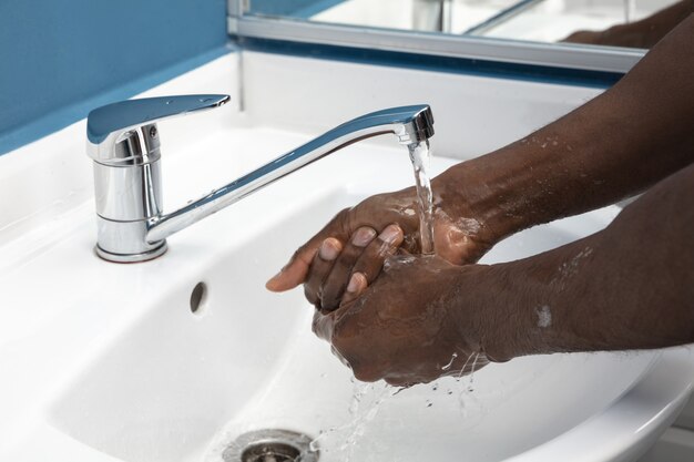 Hombre lavándose las manos cuidadosamente con jabón y desinfectante, de cerca.