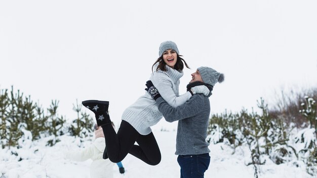 Hombre levantando a la mujer durante el paseo de invierno