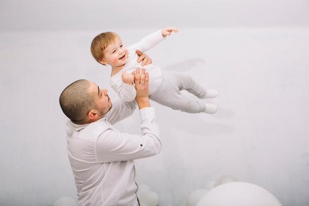 Foto gratuita hombre levantando pequeño bebé en las manos