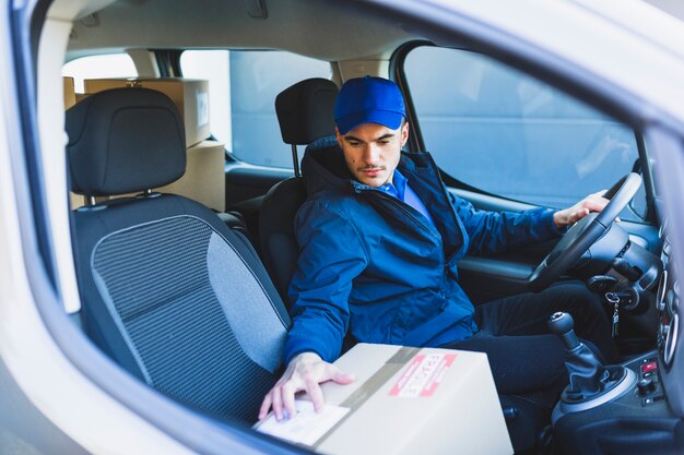 Hombre leyendo la dirección en la caja para entregar