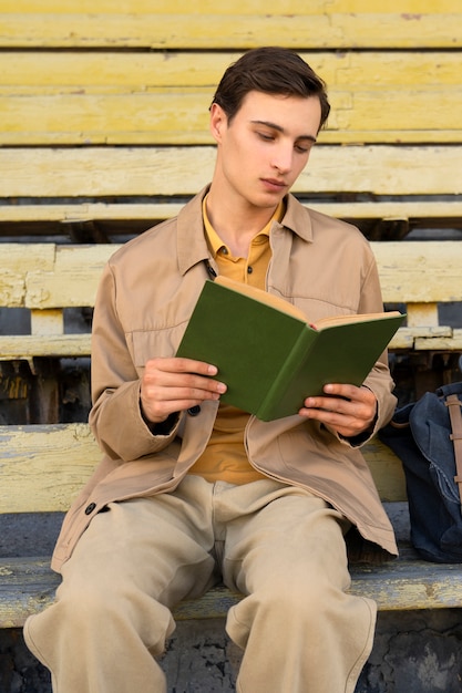 Hombre leyendo libro al aire libre plano medio