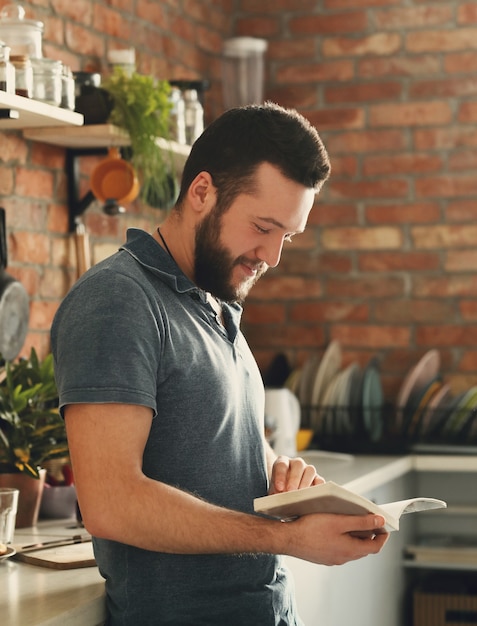 Hombre leyendo un libro de recetas en la cocina