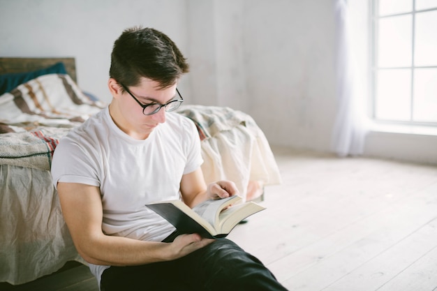 Hombre leyendo un libro en su cama en casa | Foto Premium