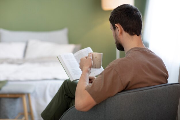 Hombre leyendo un libro y tomando café