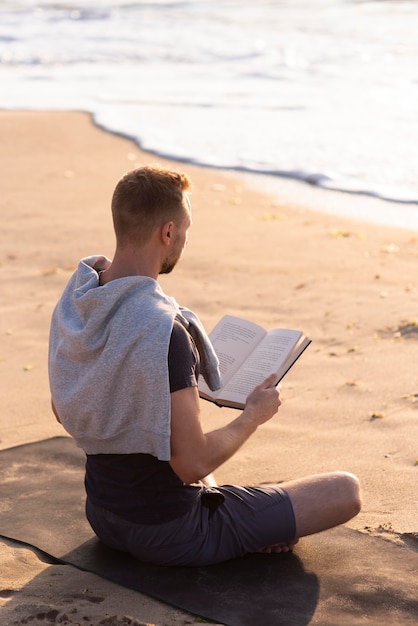 Hombre leyendo y meditando en la playa