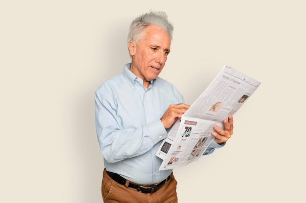 Foto gratuita hombre leyendo el periódico sobre fondo beige