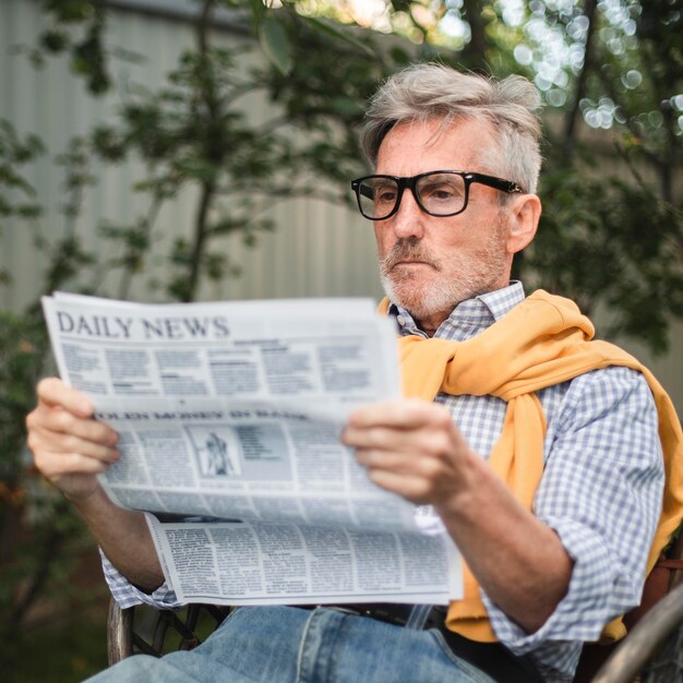 Hombre leyendo el periódico de tiro medio