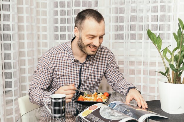 Hombre leyendo la revista durante la cena