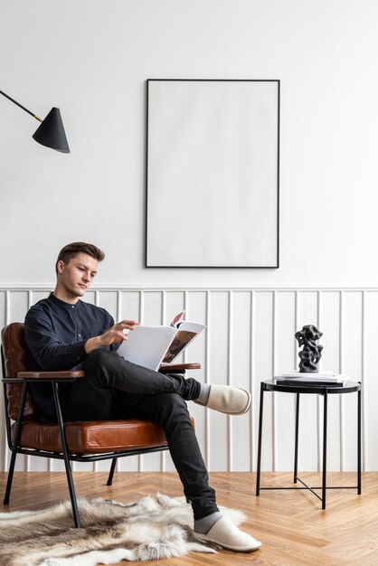 Hombre leyendo en su sala de estar con marco en blanco