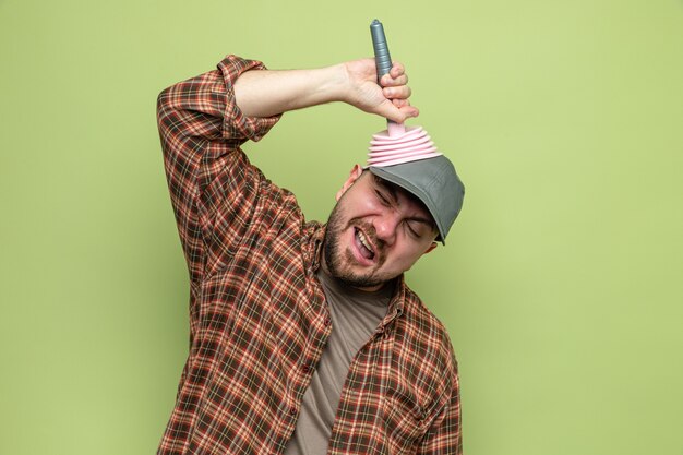 Hombre limpiador eslavo disgustado poniendo émbolo de goma en la cabeza