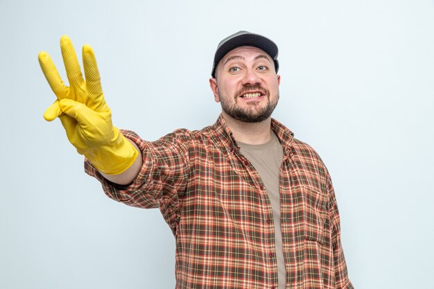 Hombre limpiador eslavo sonriente con guantes de goma gesticulando tres con los dedos