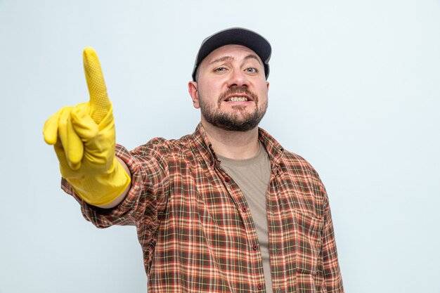 Hombre limpiador eslavo sonriente con guantes de goma mostrando su dedo índice