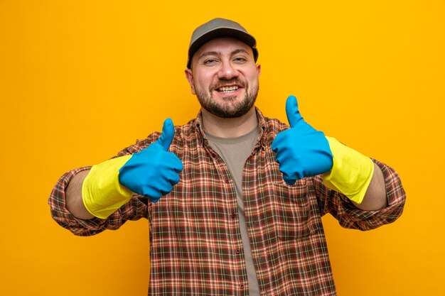 Hombre limpiador eslavo sonriente con guantes de goma pulgar hacia arriba