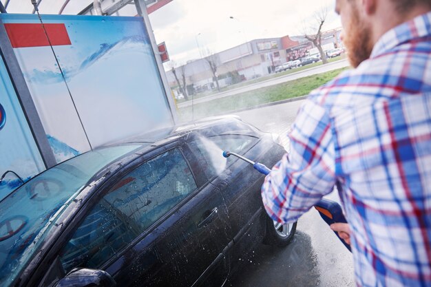 Hombre limpiando su coche en un autoservicio