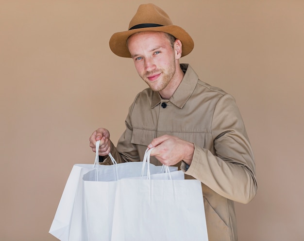 Foto gratuita hombre lindo con bolsas de compras mirando a la cámara