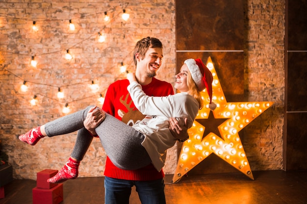 Hombre llevando novia enfrente de decoración de estrella de navidad