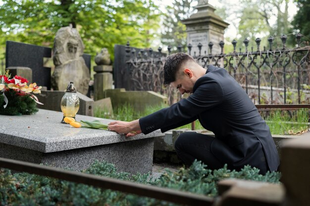 Hombre de luto trayendo tulipanes en el cementerio