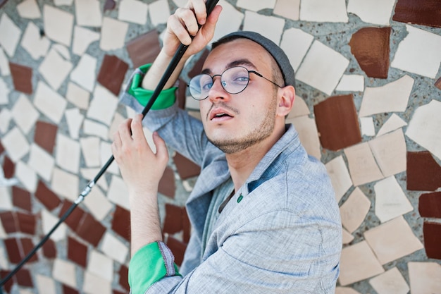 Hombre macho con estilo soñador con sombrero de traje gris y gafas posadas en el techo