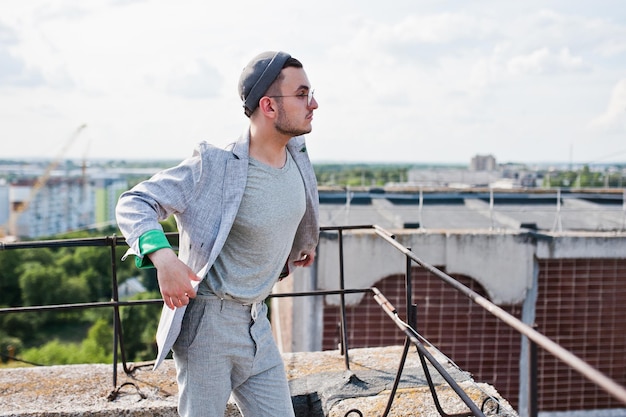 Hombre macho con estilo soñador con sombrero de traje gris y gafas posadas en el techo