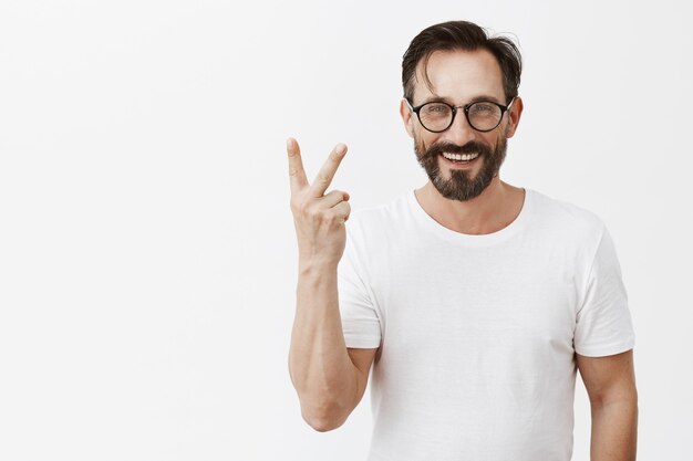 Hombre maduro barbudo feliz guapo con gafas posando